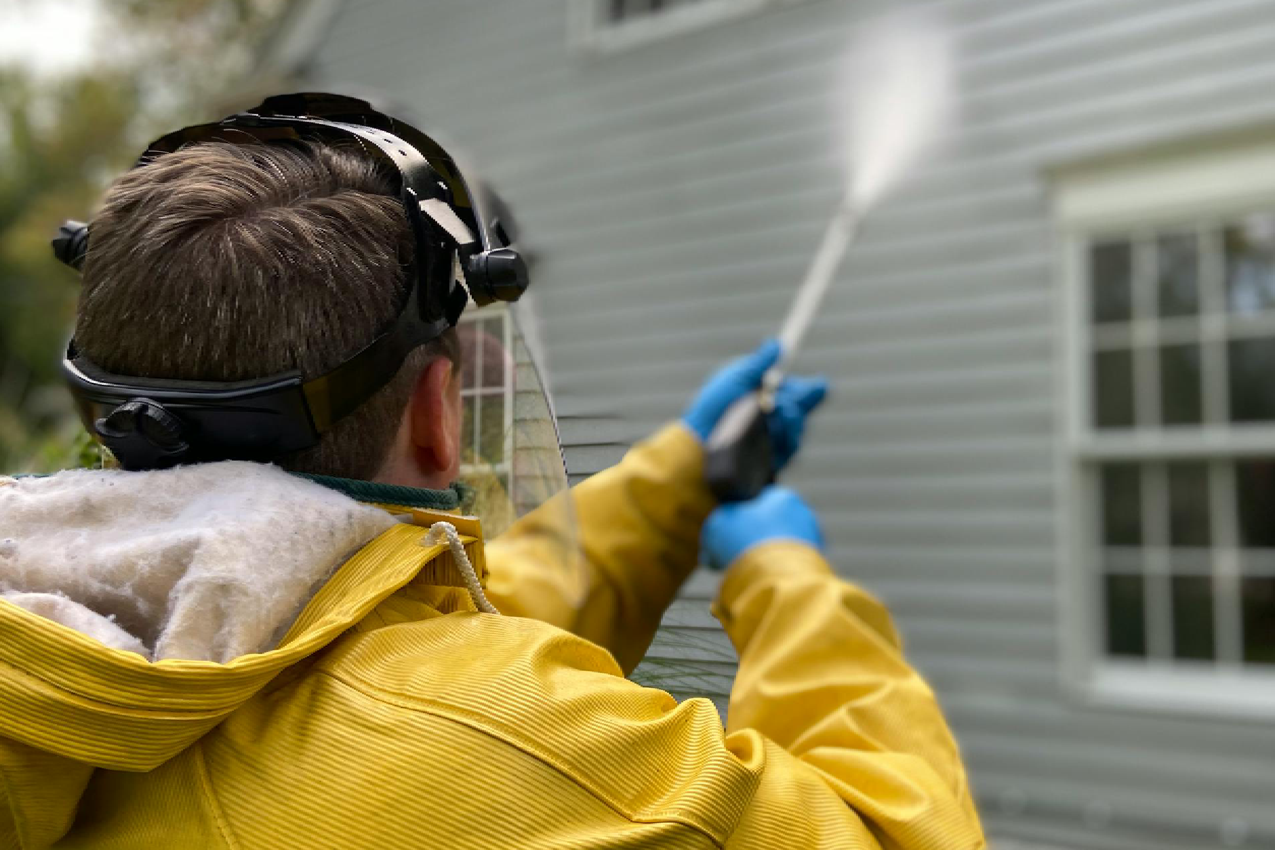 Back View of a Person Pressure Washing a House