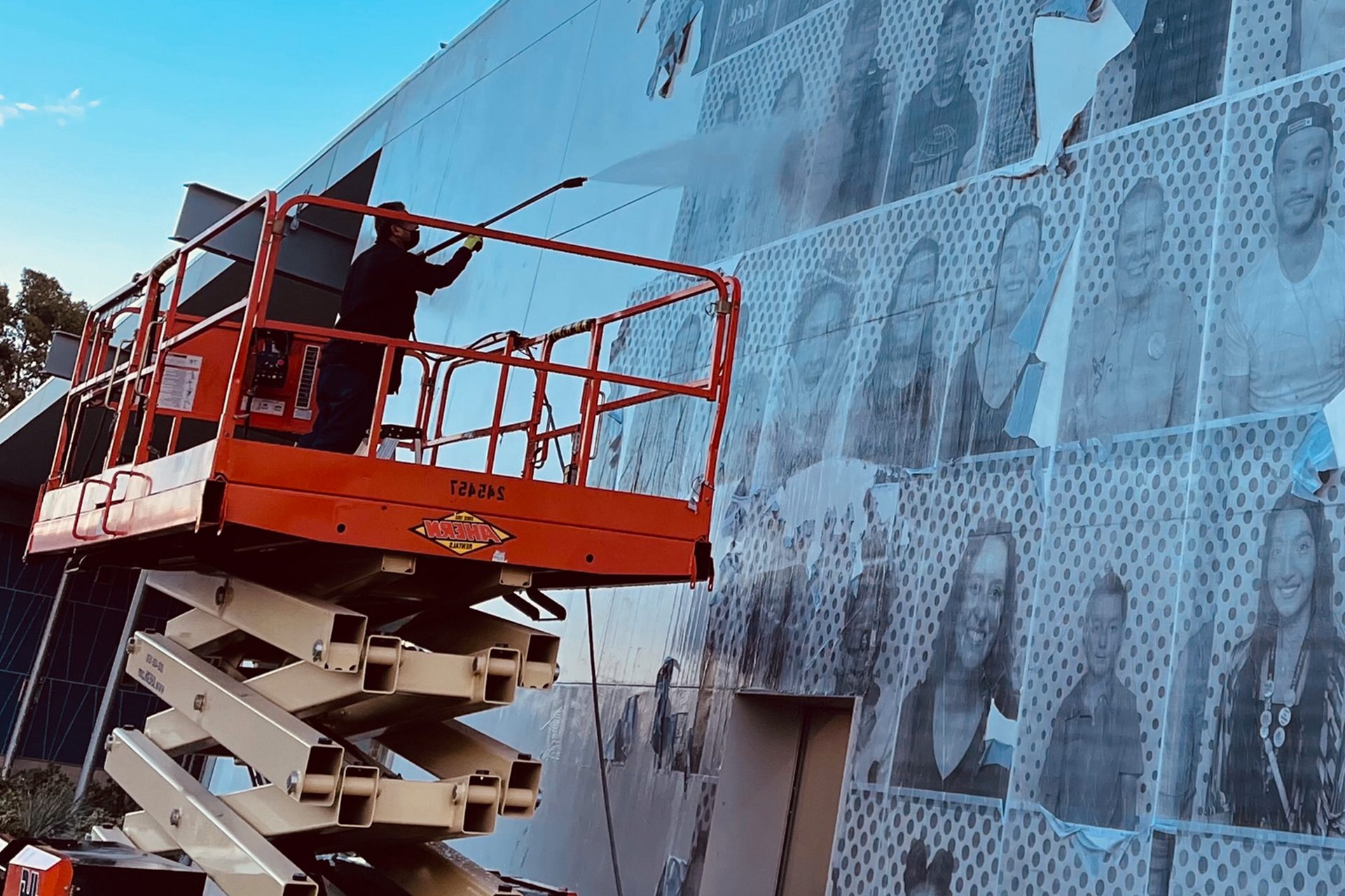 A man skillfully paints a vibrant mural on the side of a building, showcasing his artistic talent and creativity