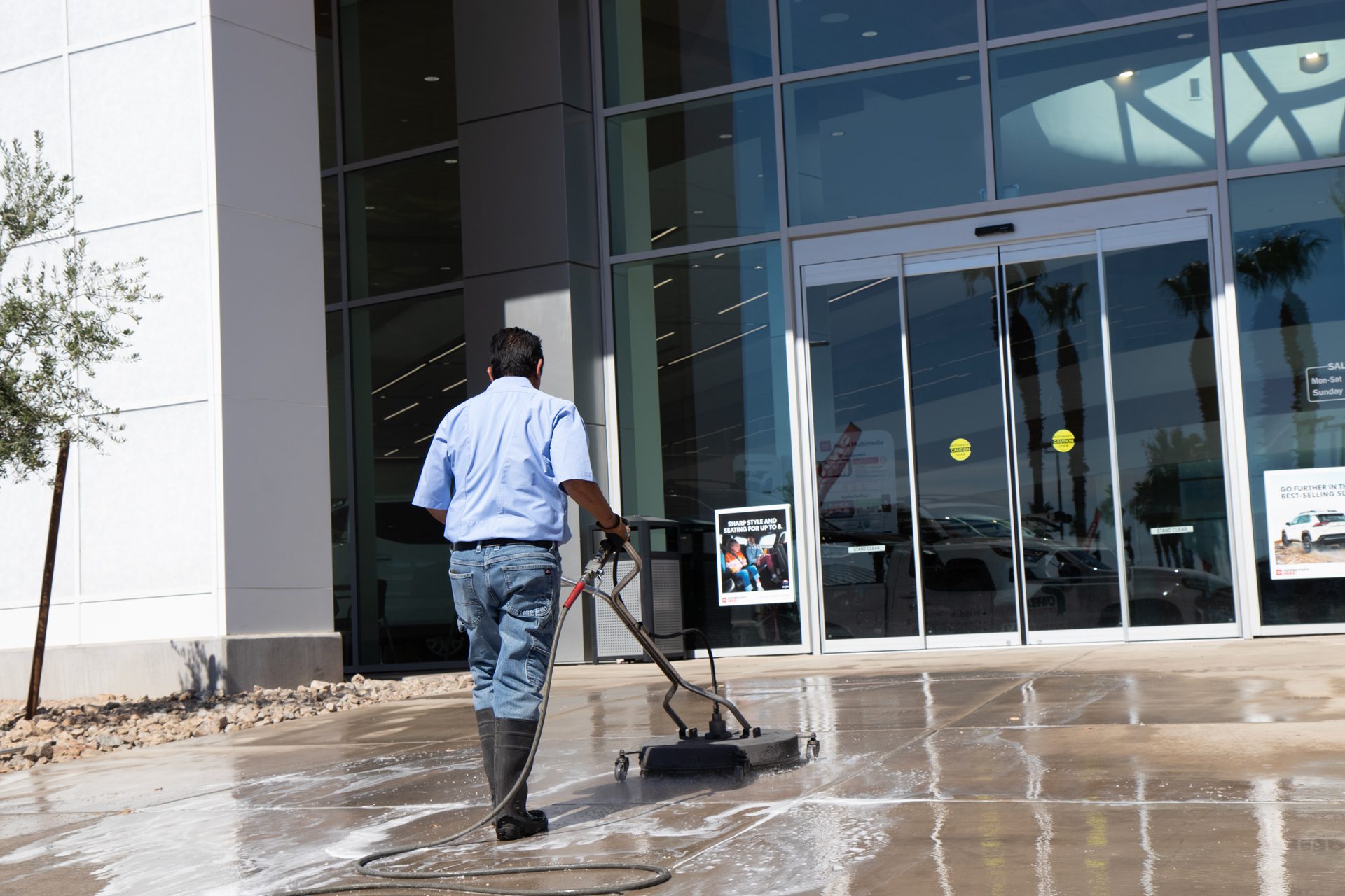 A man operates a machine to clean the sidewalk, ensuring a tidy and well-maintained outdoor space