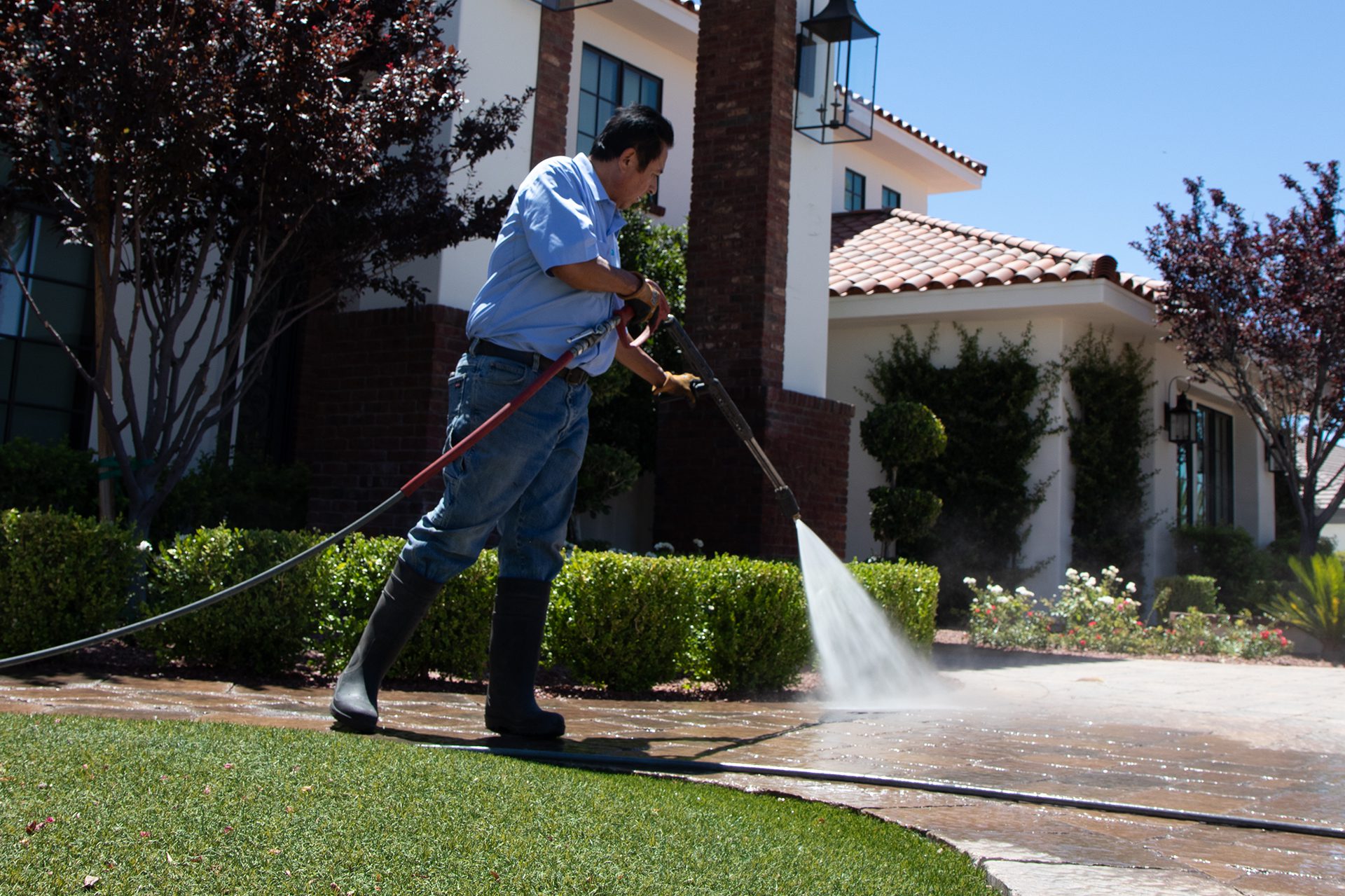 A man diligently cleans a driveway, ensuring a tidy and well-maintained outdoor space